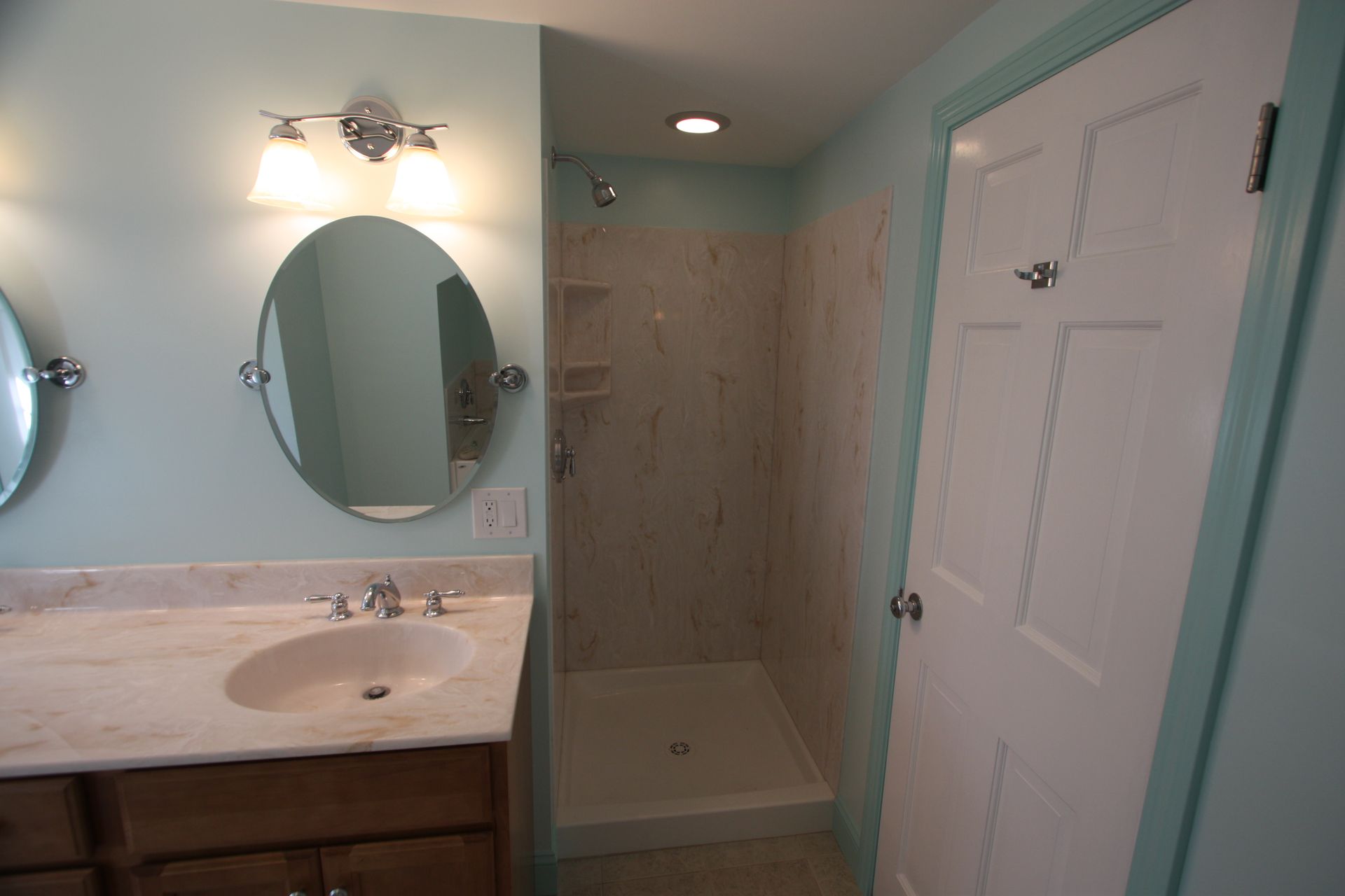 A bathroom with a sink, a mirror, and a walk in shower.