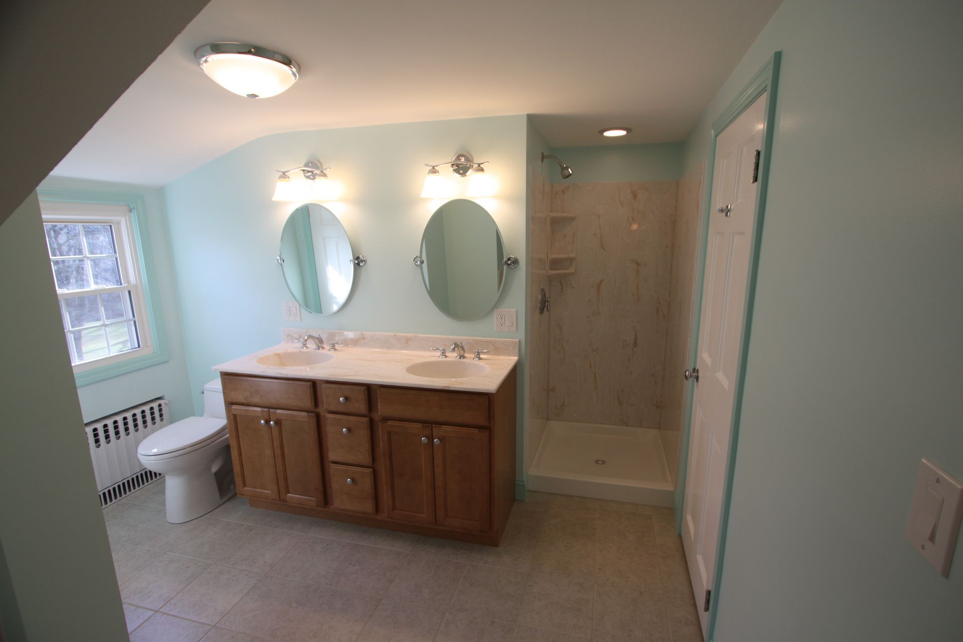 A bathroom with two sinks, a toilet, and a walk in shower.