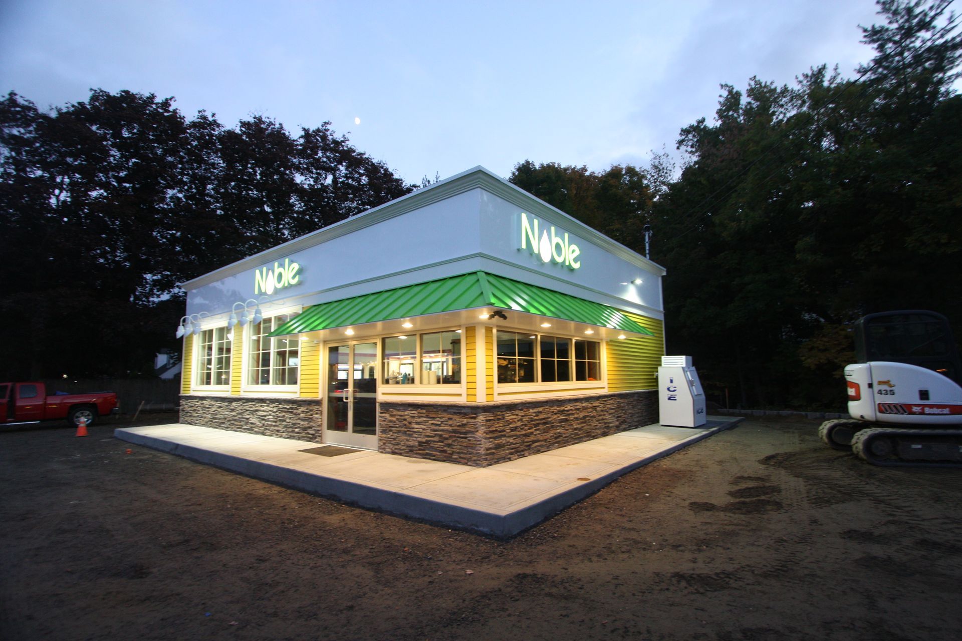 A white building with a green awning that says noble.