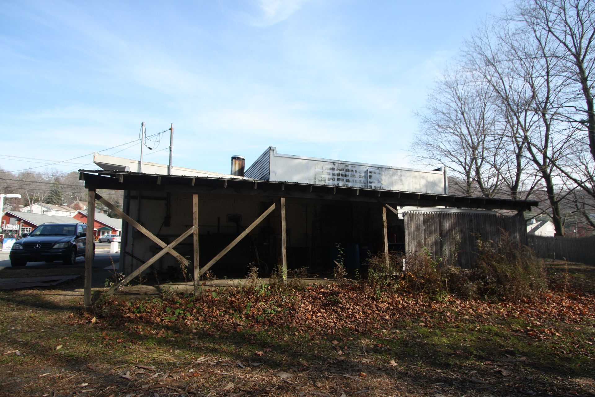 A car is parked in front of an abandoned building.