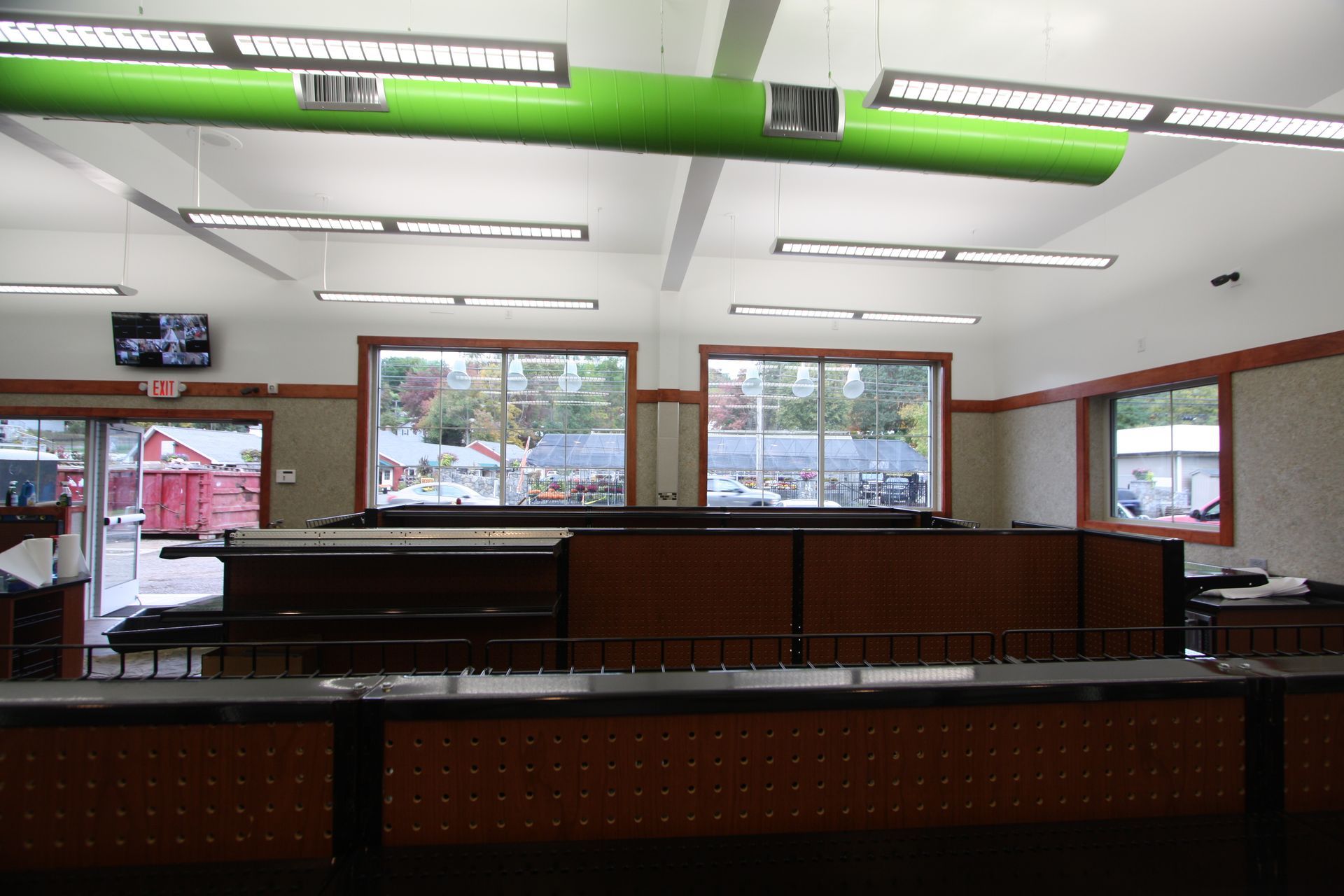 A large room with lots of windows and a green duct hanging from the ceiling.