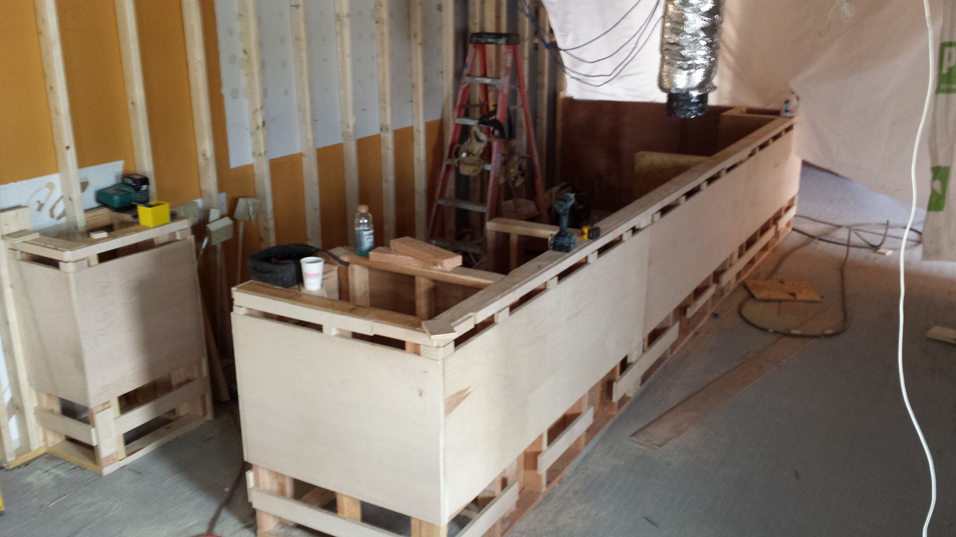 A large wooden box is sitting in a room under construction.