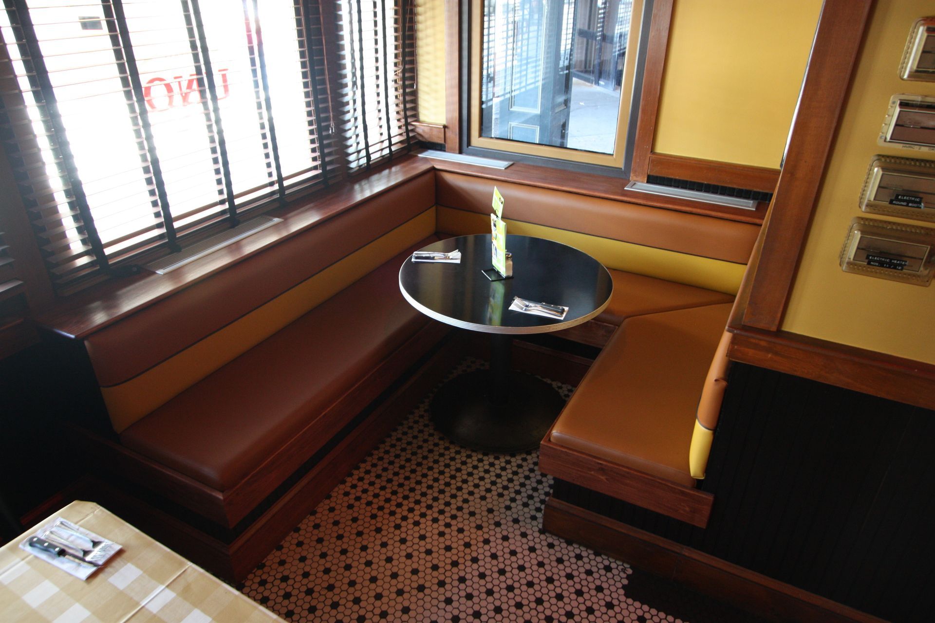 A restaurant booth with a round table and a window.