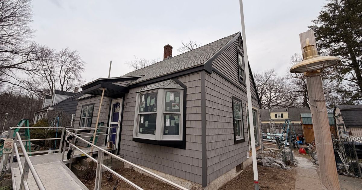 Gray house with black trim under renovation, surrounded by scaffolding and a worksite
