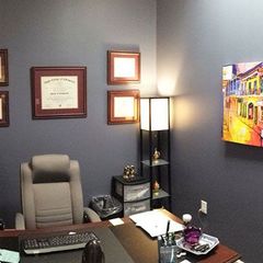 An office with a painting on the wall and a diploma on the wall