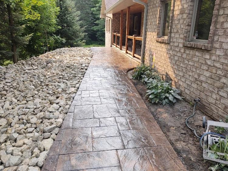A stone walkway leading to a brick house surrounded by rocks.