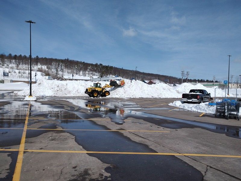 A snow plow is clearing snow from a parking lot