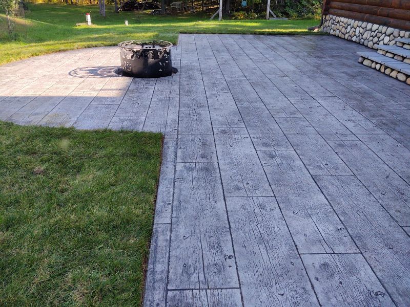A concrete patio with a fire pit in the middle of it.