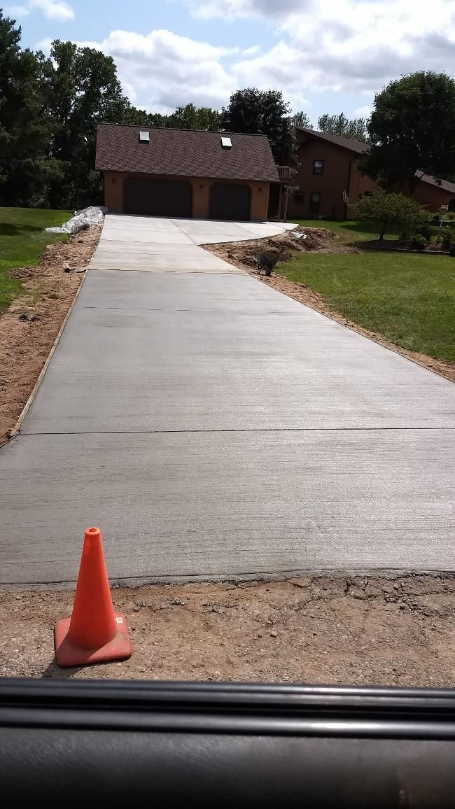 A concrete driveway with an orange cone on the side of it