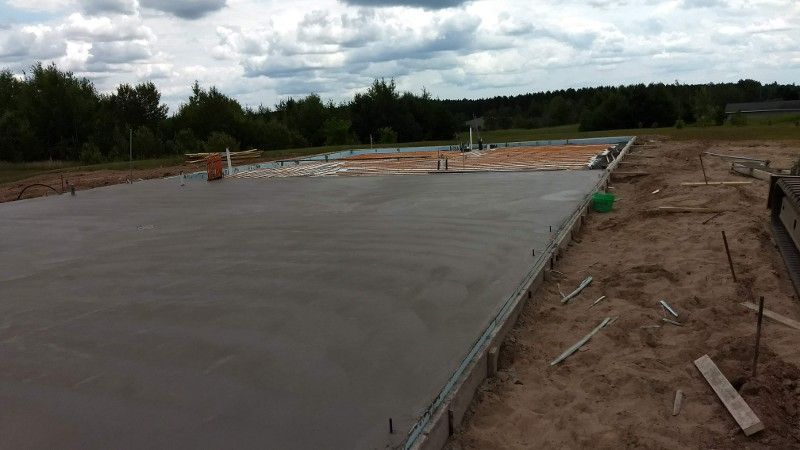 A concrete floor is being built in a field with trees in the background.