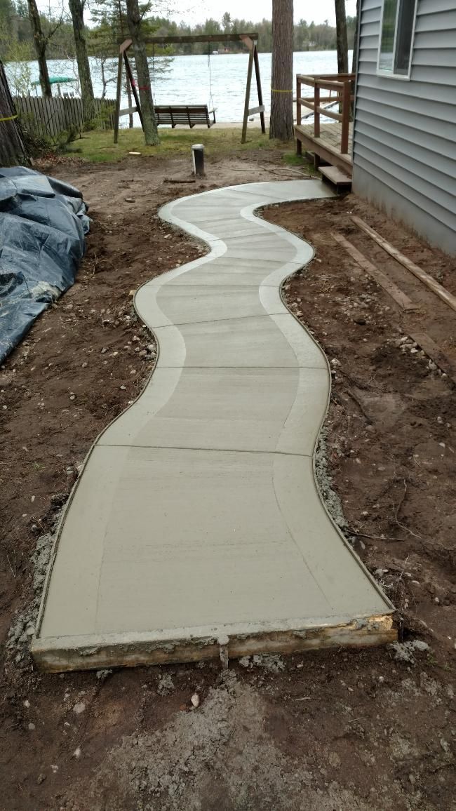 A concrete walkway is being built in front of a house.