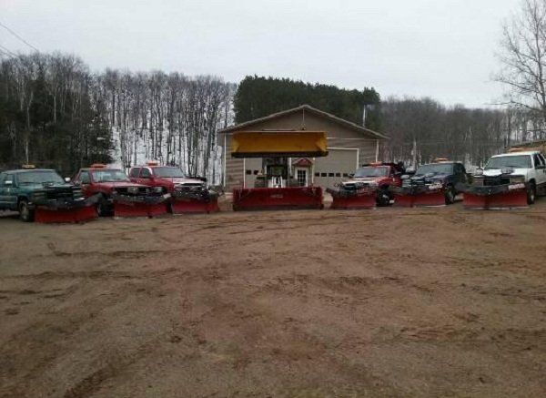 A row of snow plows are parked in front of a building.