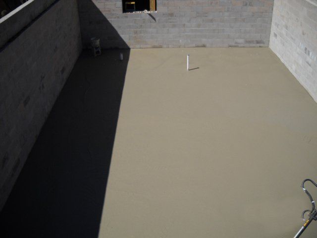 A concrete floor is being poured in a building under construction.