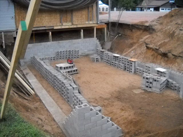 A brick wall is being built in a dirt area