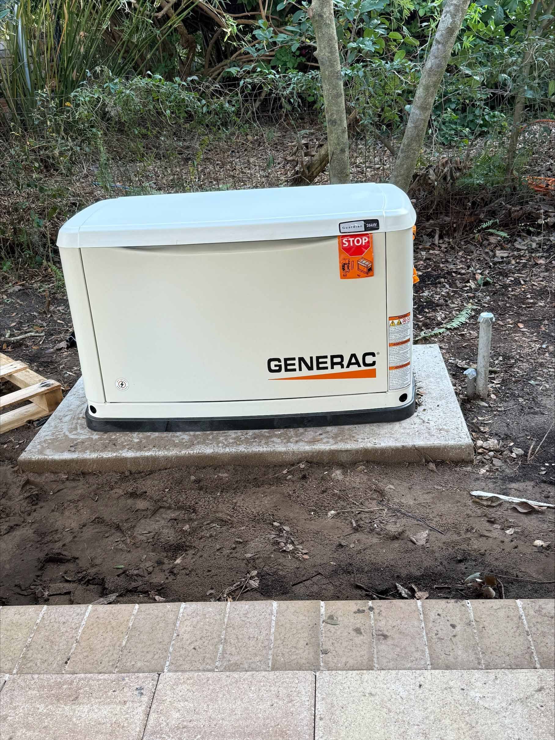 Generator (Generac brand) on a concrete pad in a yard. Beige and gray tones, with trees in background.