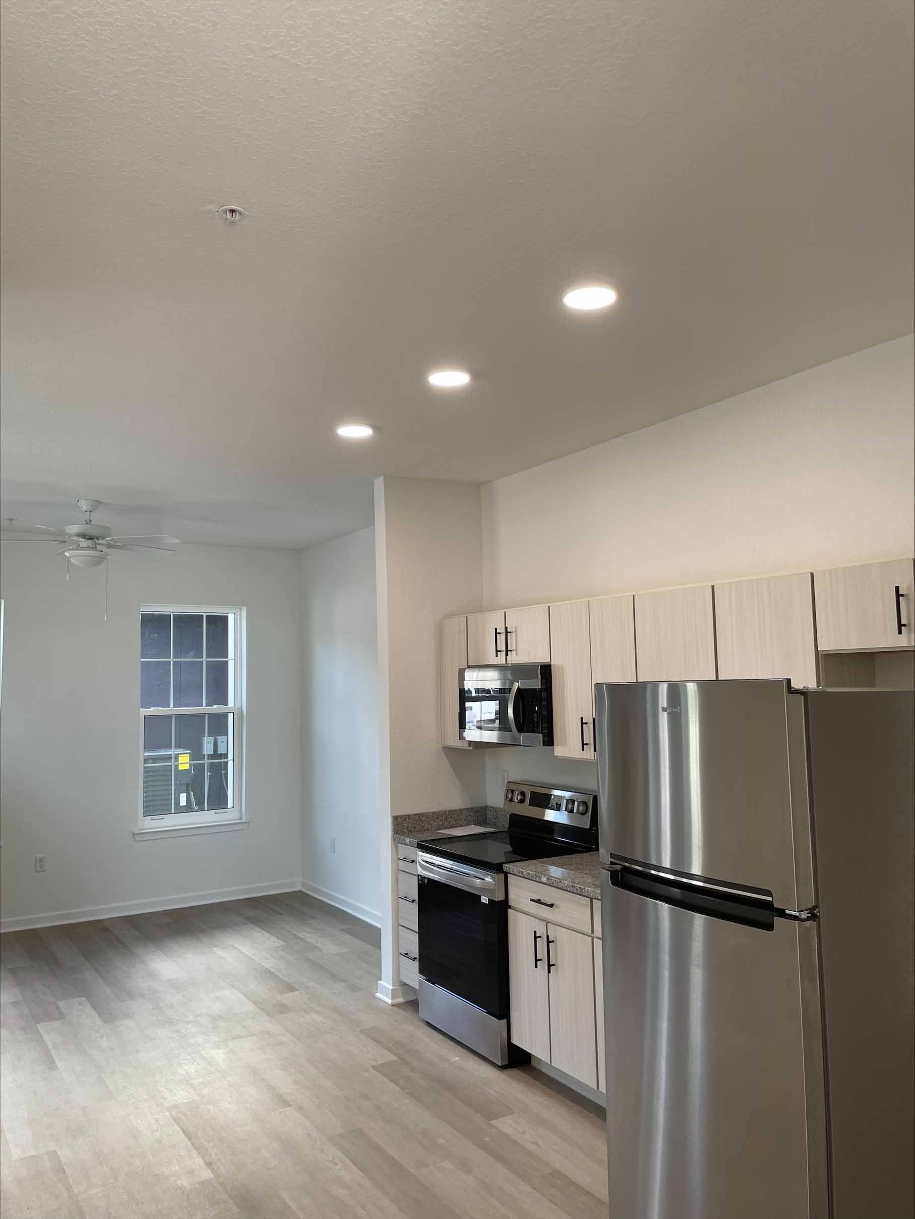 Bright kitchen with stainless steel appliances, white cabinets, and wood-look flooring.