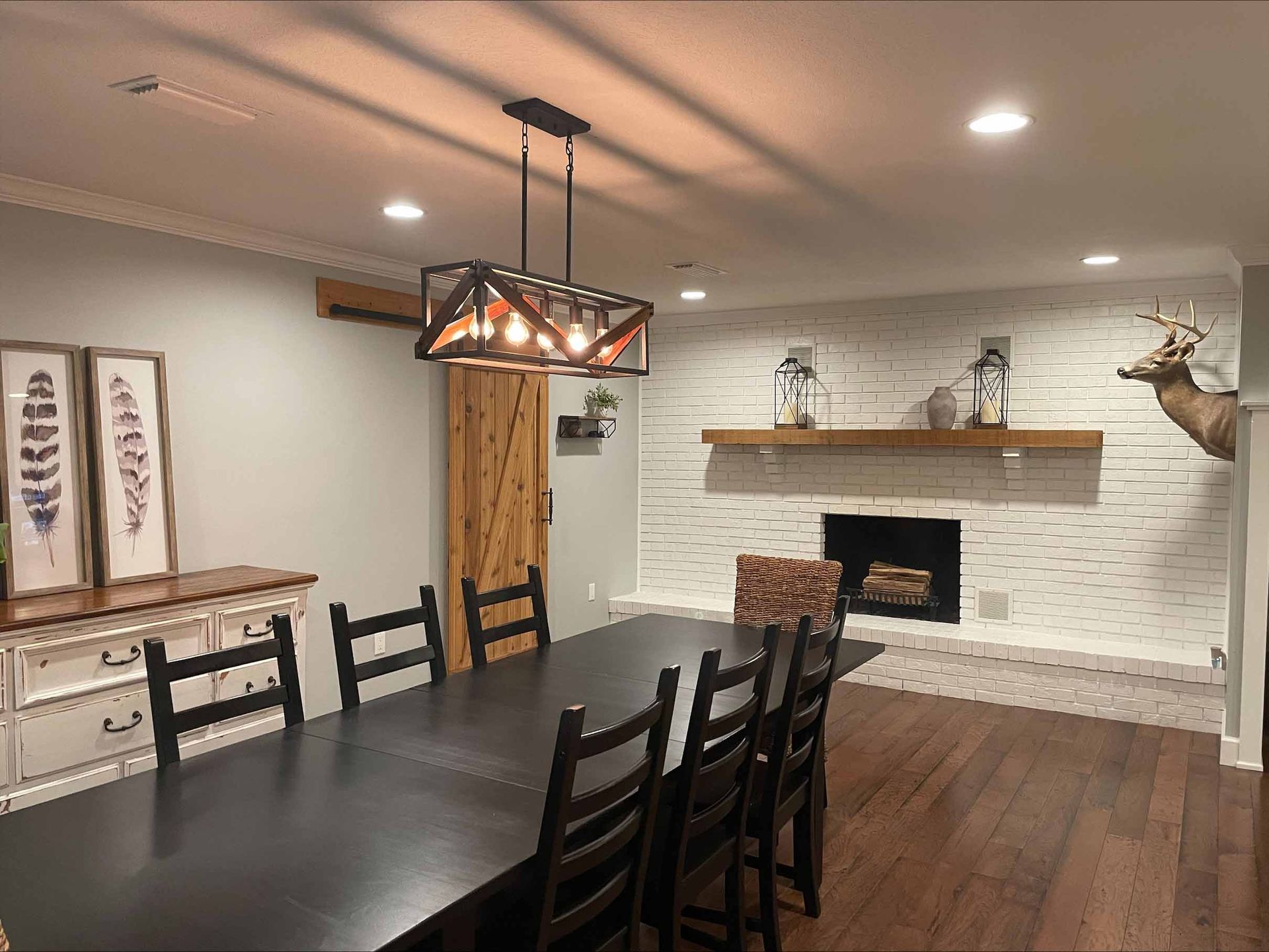 Dining room with black table, chairs, fireplace, and rustic light fixture.