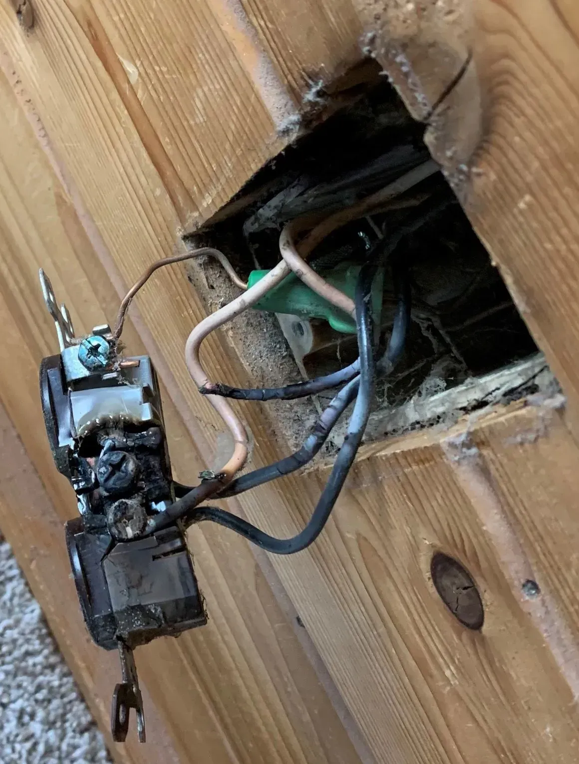 A burnt outlet with incorrect wiring which led to arcing and damage behind the outlet.
