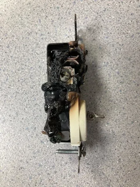 Side view of melted duplex outlet showing significant heat damage