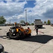 A machine is laying asphalt in a parking lot.