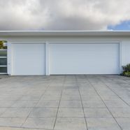 A white garage door with a concrete driveway in front of it.