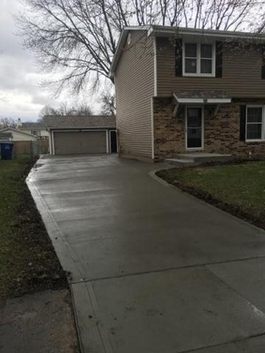 A concrete driveway leading to a house with a garage.