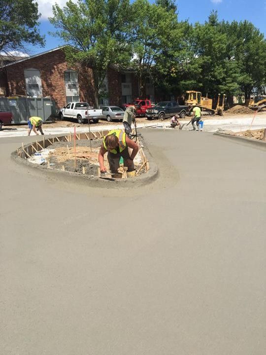 A group of construction workers are working on a concrete driveway.