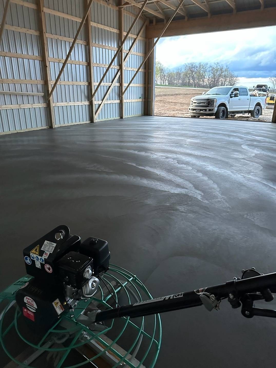 A concrete trowel is being used to finish a concrete floor in a building.