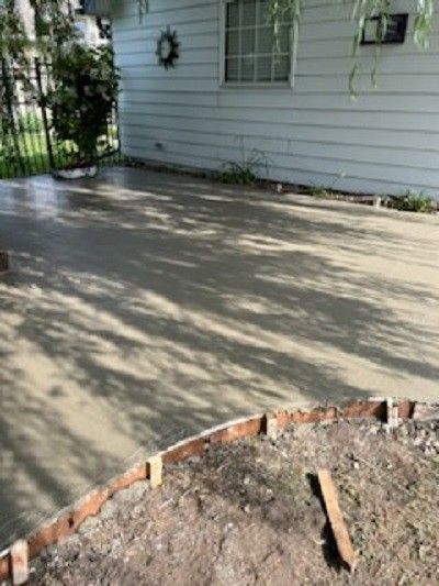 A concrete driveway is being built in front of a house.
