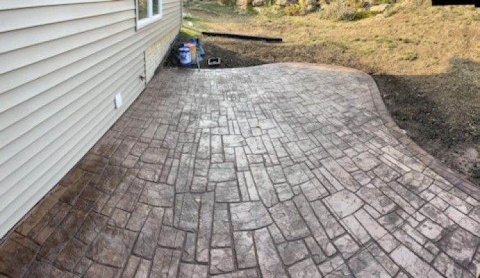A patio with a brick pattern is sitting next to a house.