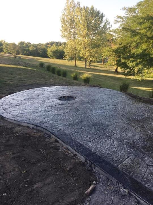 A concrete patio with a fire pit in the middle of it.