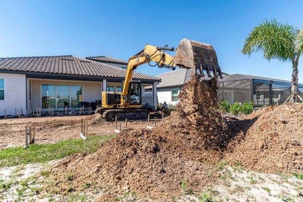 An excavator is on a job site digging the foundation for a new pool