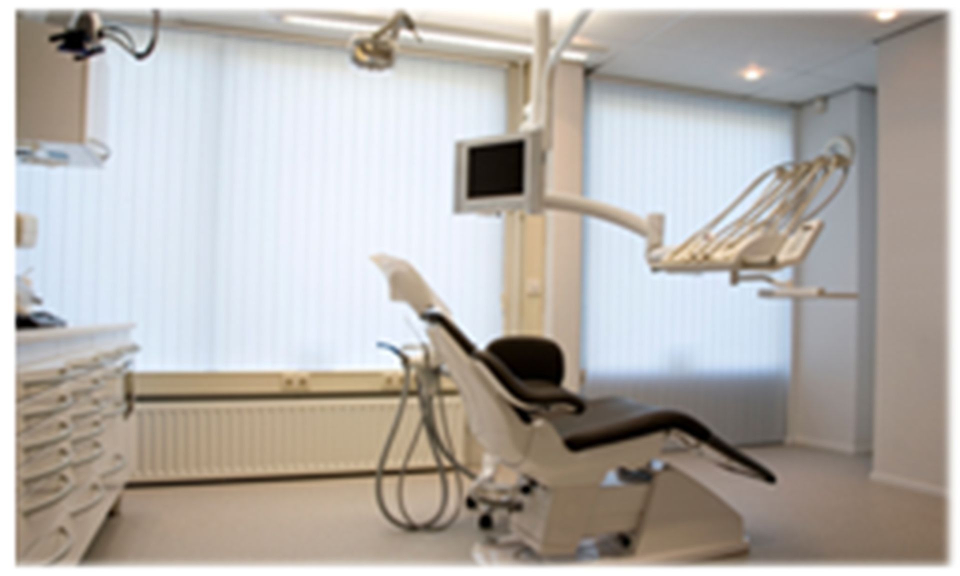 Dental operatory with chair, equipment, and window blinds.