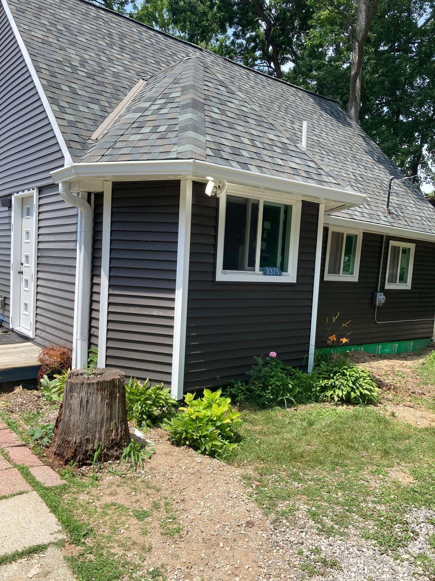 Dark gray house with white trim, gray roof, and landscaping.