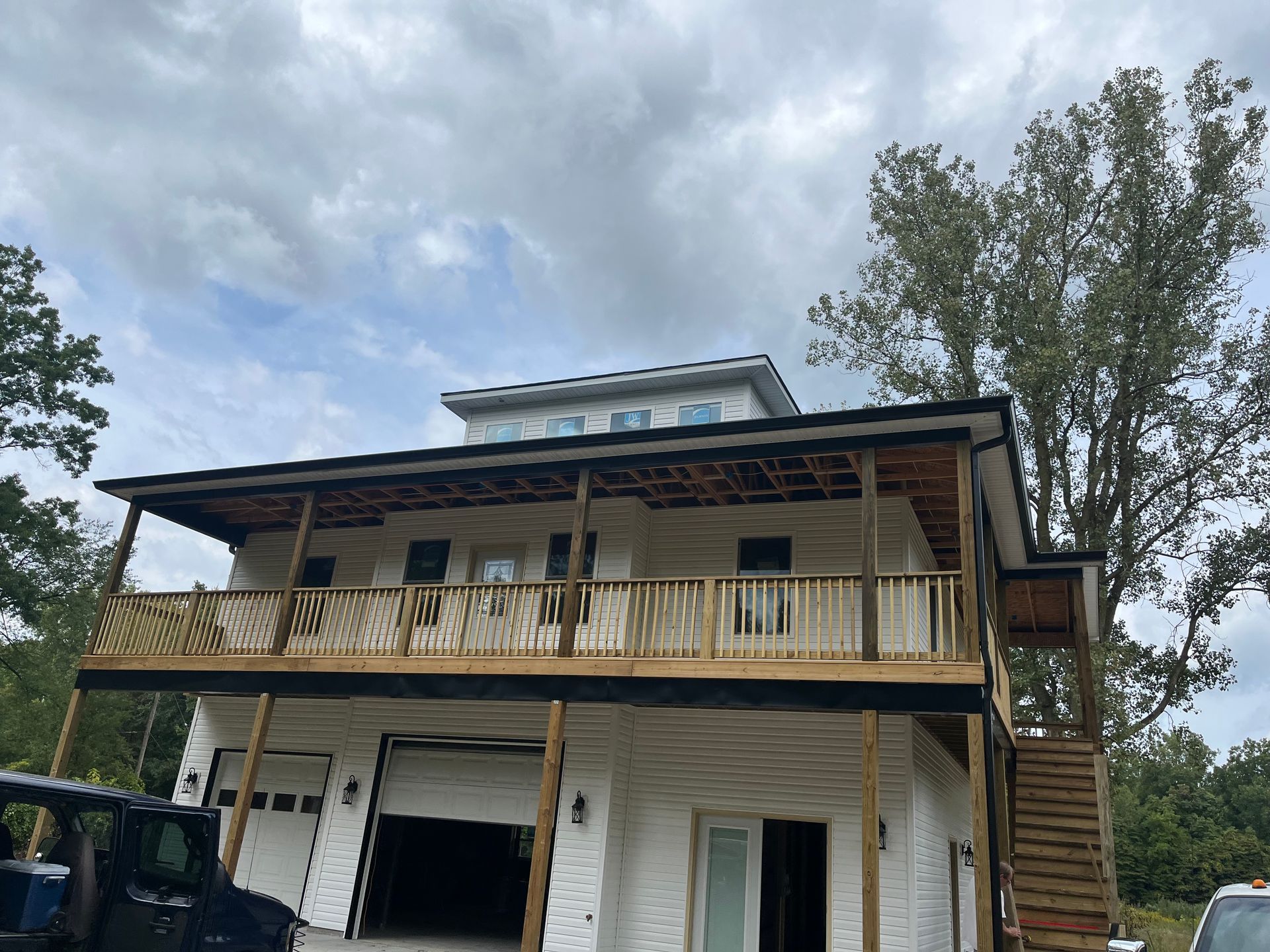 Two-story house with white siding and black trim, a large porch, and an attached garage.