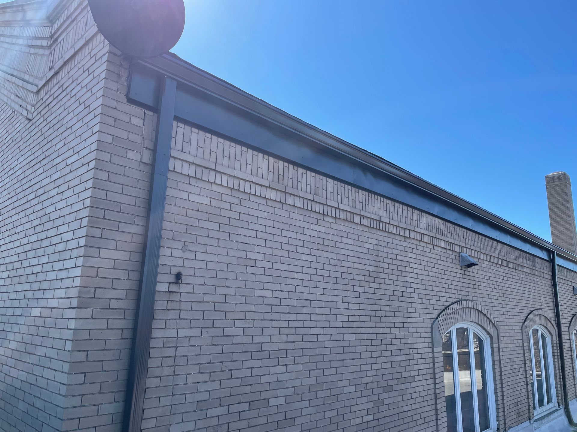 Brick building exterior with black trim, blue sky.