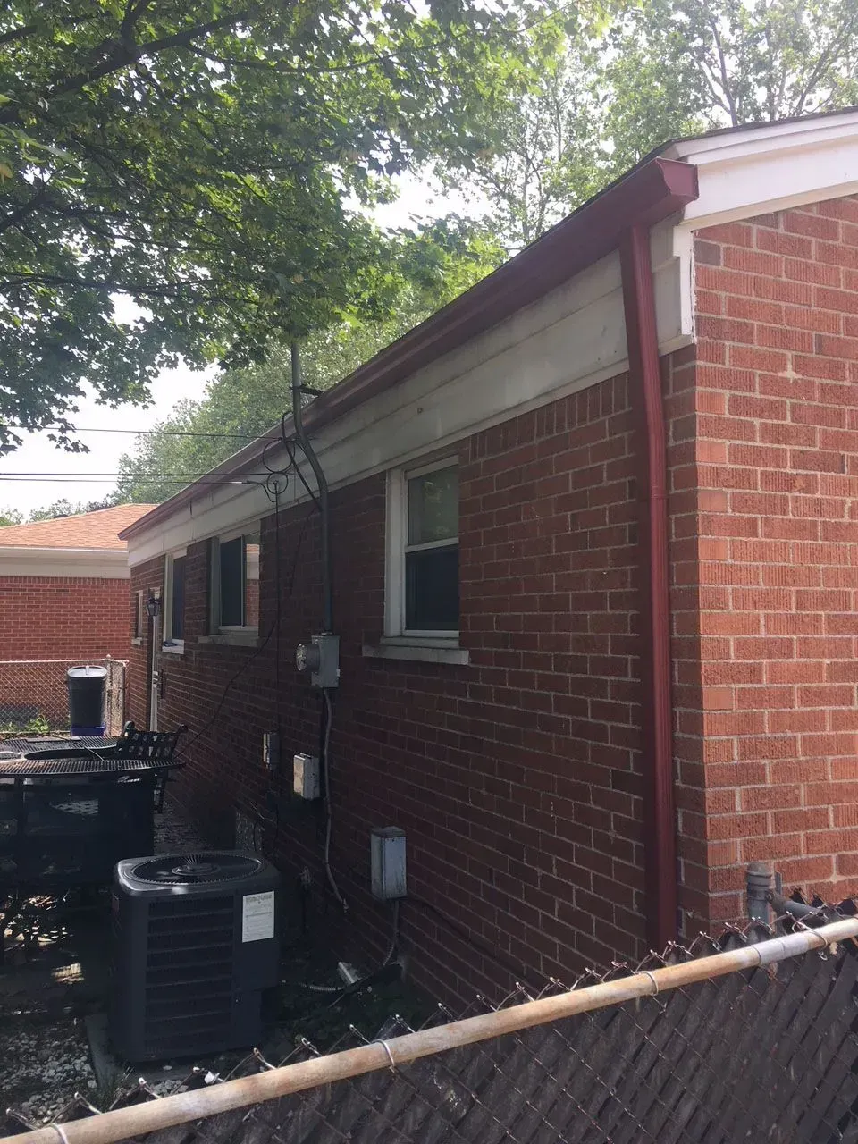 Red brick building with red trim, several windows, and an air conditioning unit.