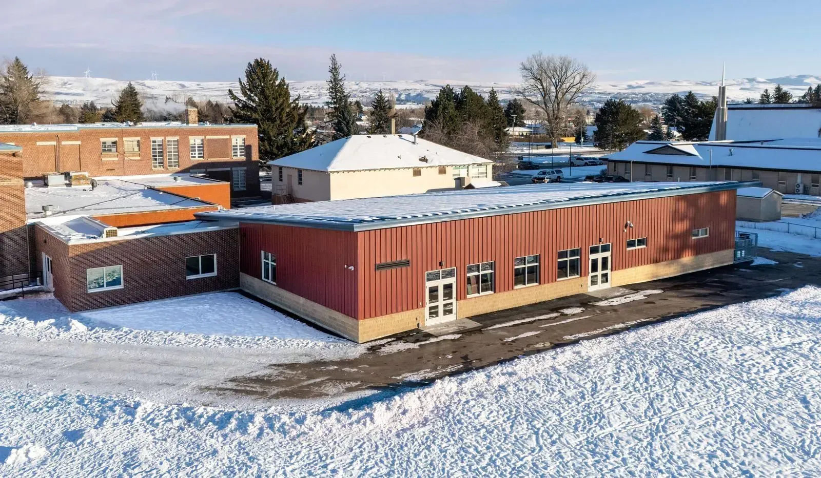 An aerial view of a large red building covered in snow.