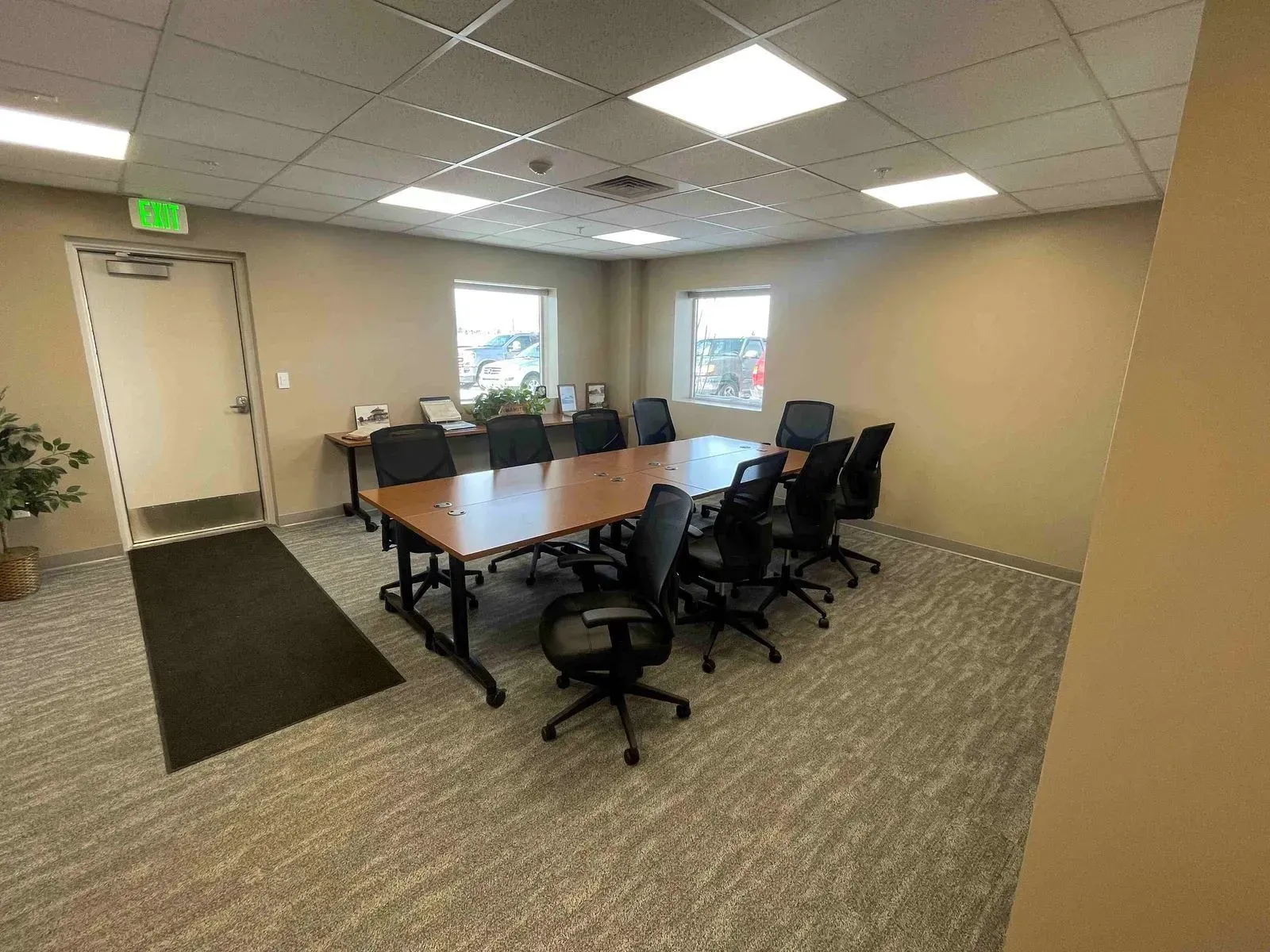 Conference room with long table, black chairs, windows, and beige walls