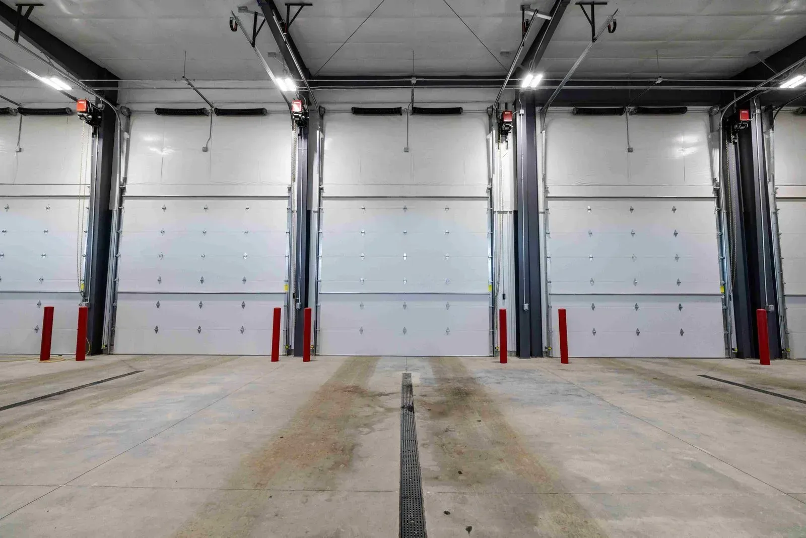 A warehouse with a lot of white doors and red poles.