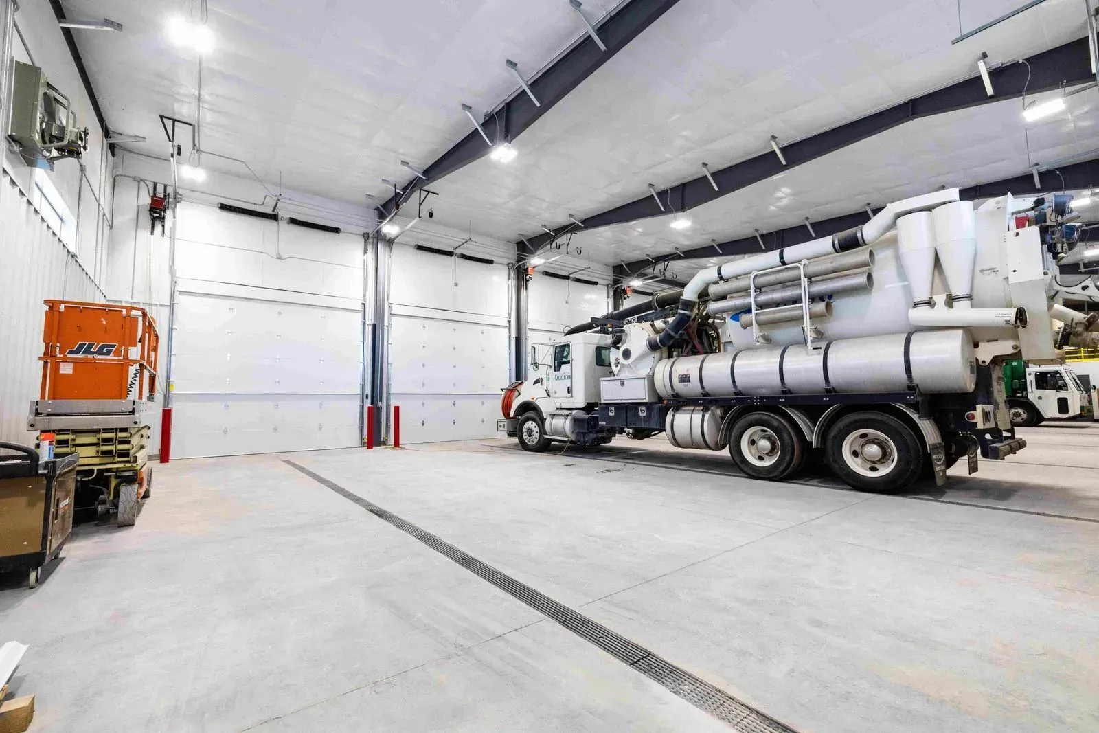 Two trucks are parked in a large garage.