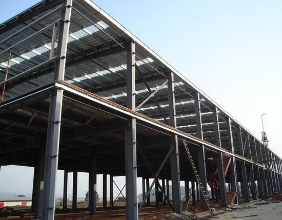 Steel-framed building under construction, with exposed beams, girders, and a corrugated roof.