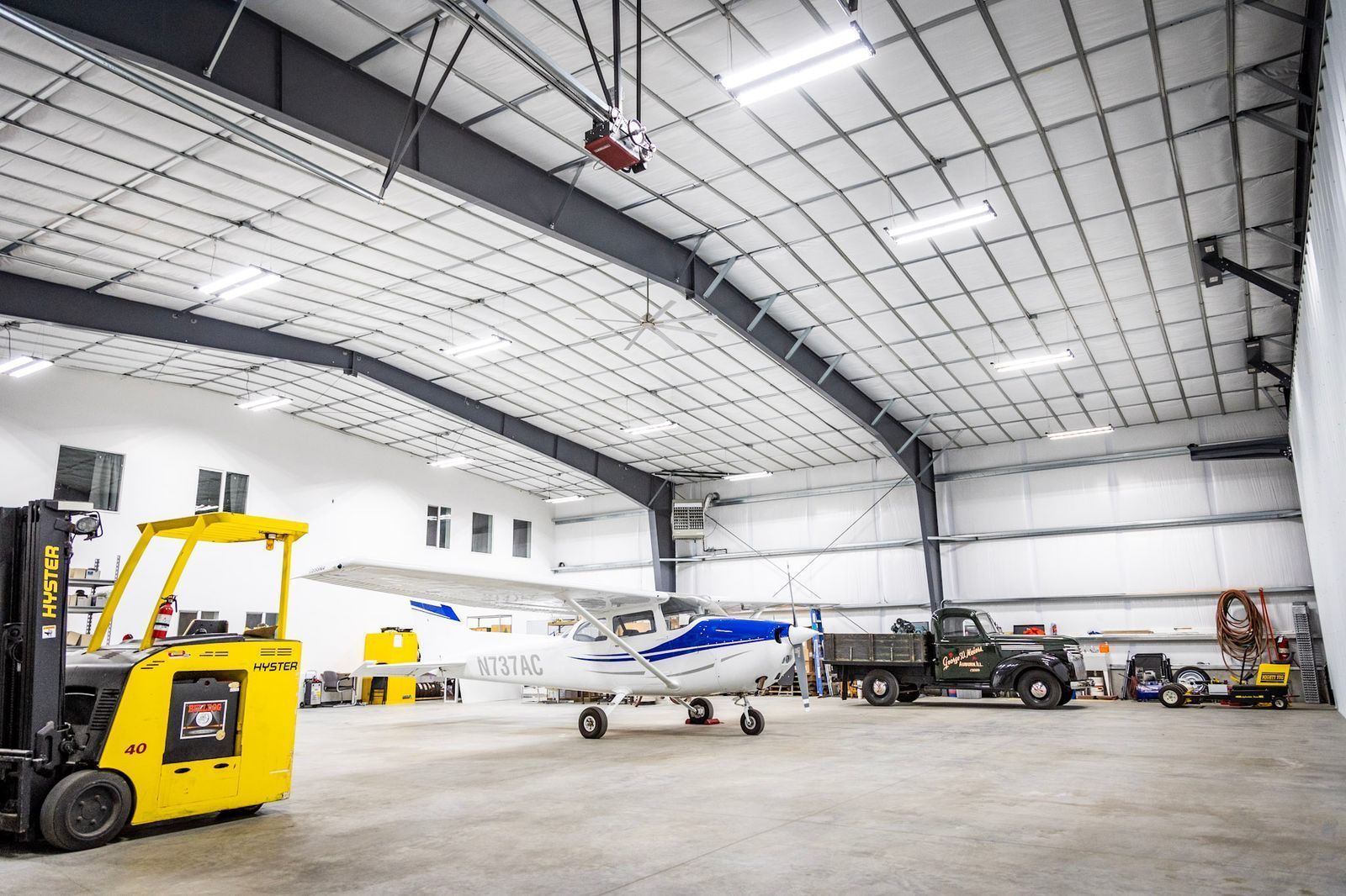 A plane is parked in a hangar next to a forklift.