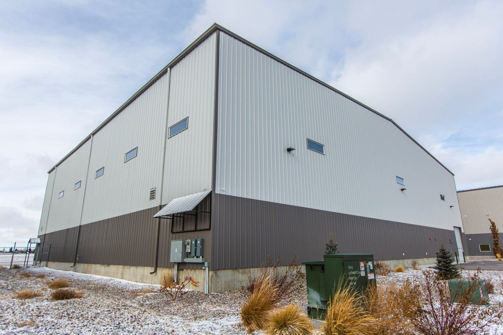 A large building with a lot of windows is sitting in the middle of a snowy field.