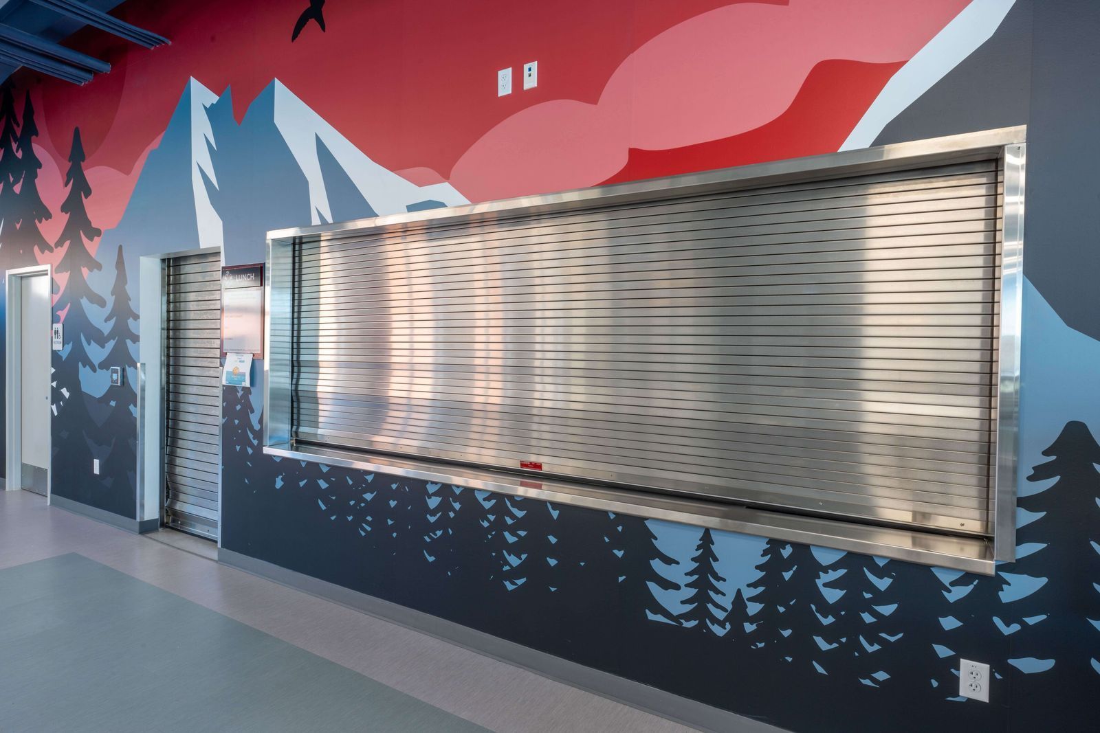 A wall with a painting of mountains and trees on it