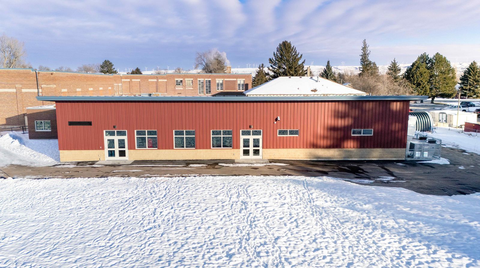 A large red building is sitting in the middle of a snowy field.