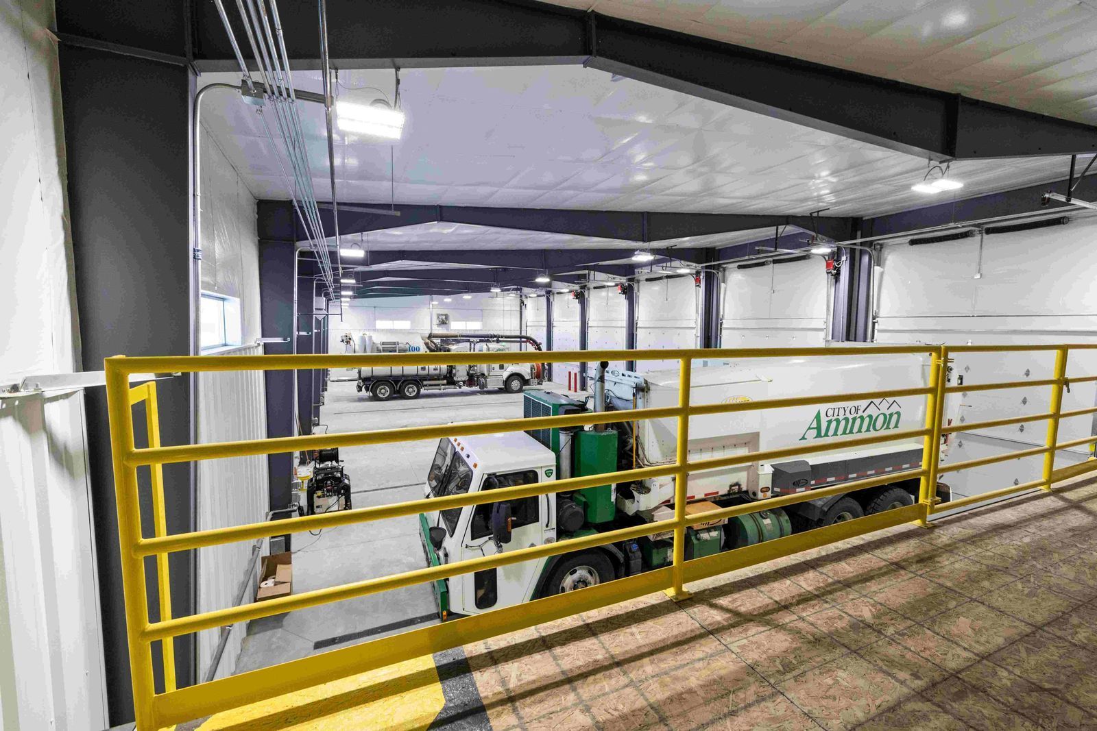 A truck is parked in a garage with a yellow railing.