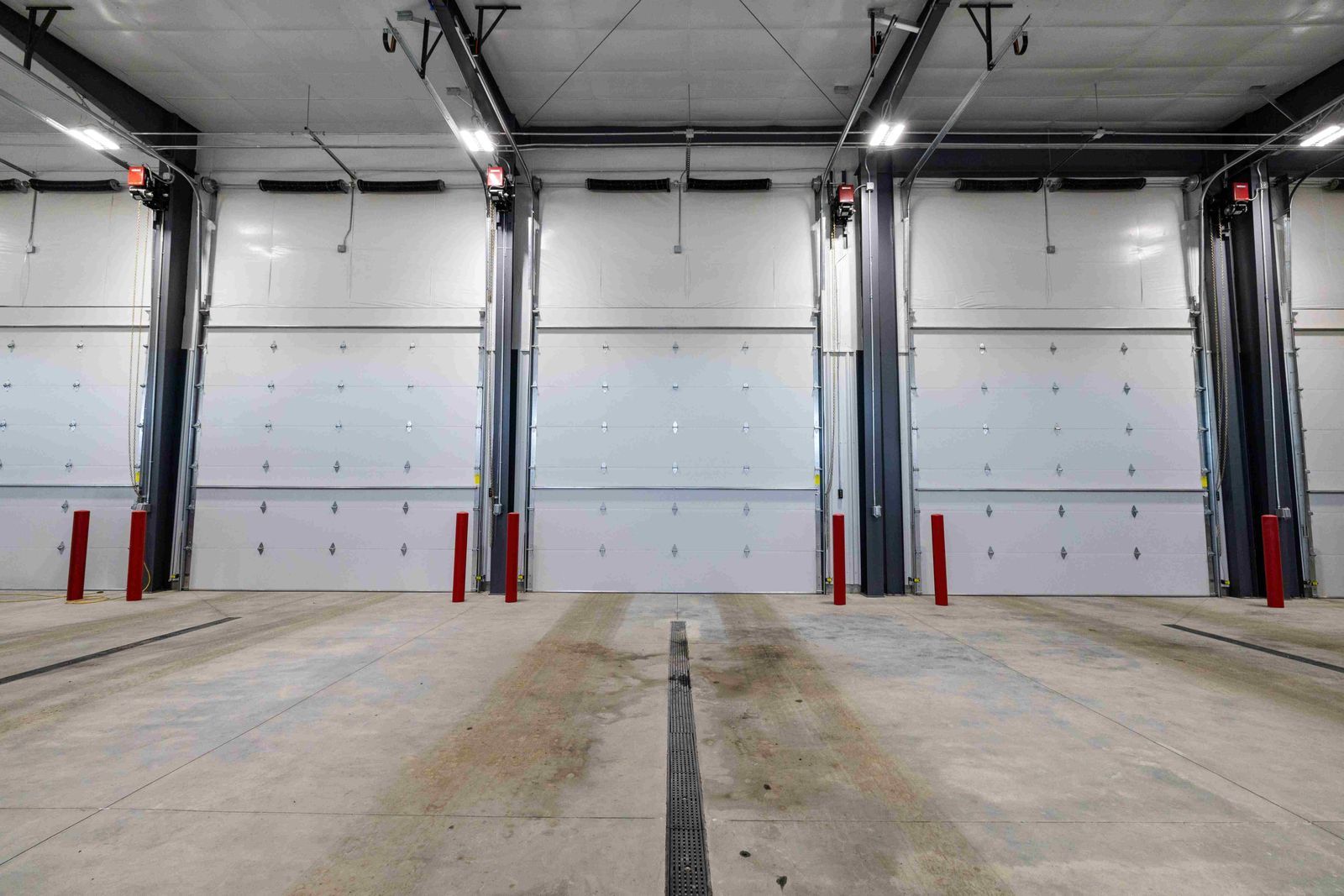 A warehouse with a lot of white doors and red poles.