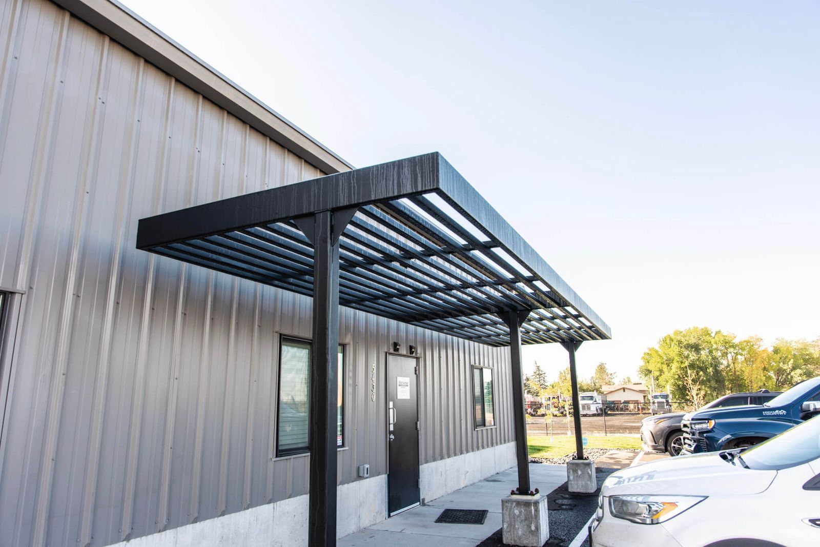Black metal awning over a door on a gray metal building
