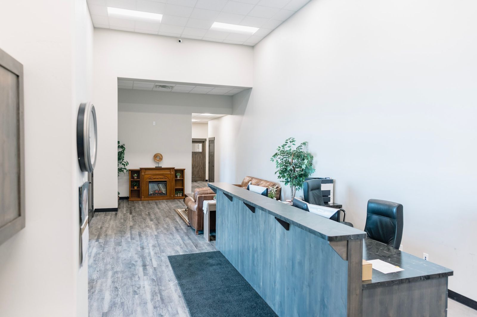 A lobby with a blue desk and a fireplace in the background